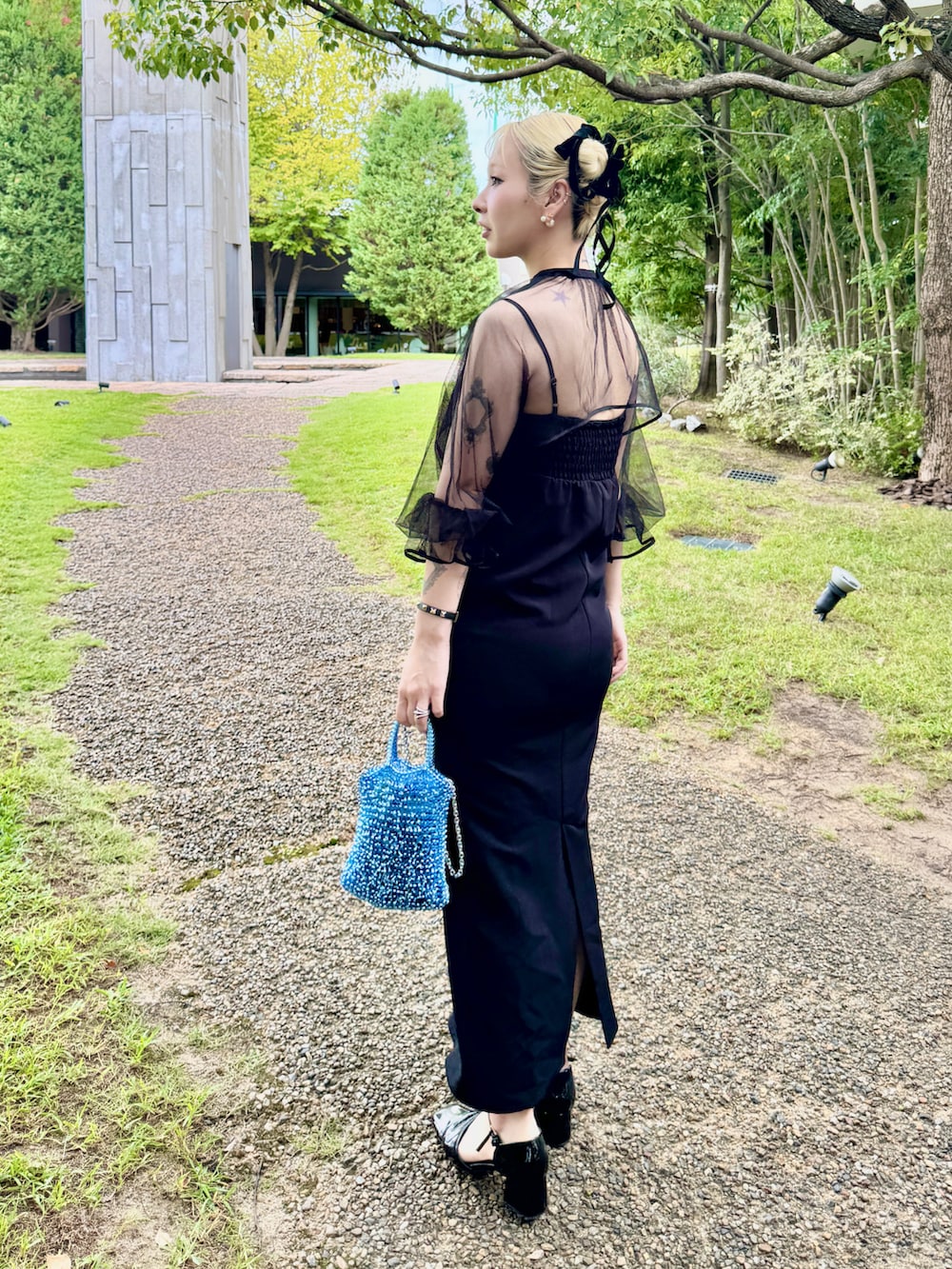 ブラック系のワンピース、ブルー系のショルダーバッグ、ブラック系のパンプスを着用したレディースの秋コーディネートの2枚目の写真