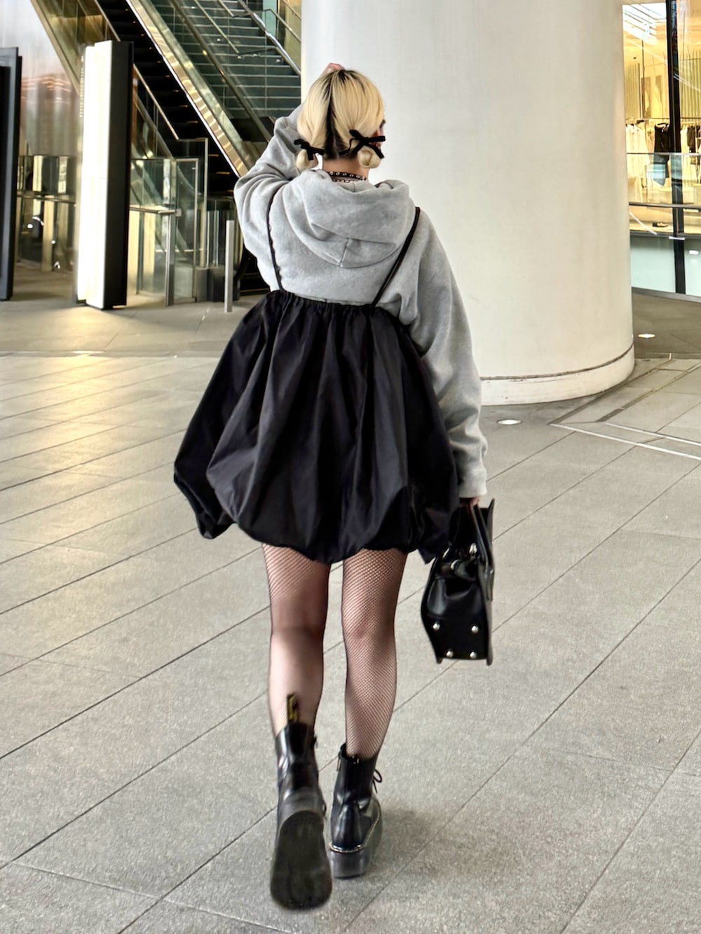 ブラック系のバッグ、グレー系のパーカー、ブラック系のワンピースを着用したレディースの春コーディネートの2枚目の写真