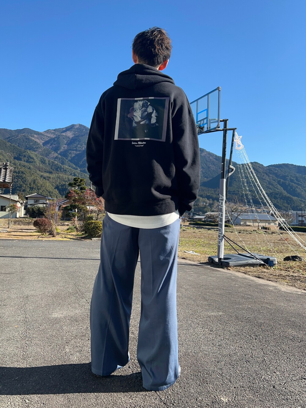 ブラック系のパーカー、グレー系のスラックス、ブラック系のサンダルを着用したメンズの冬コーディネートの2枚目の写真