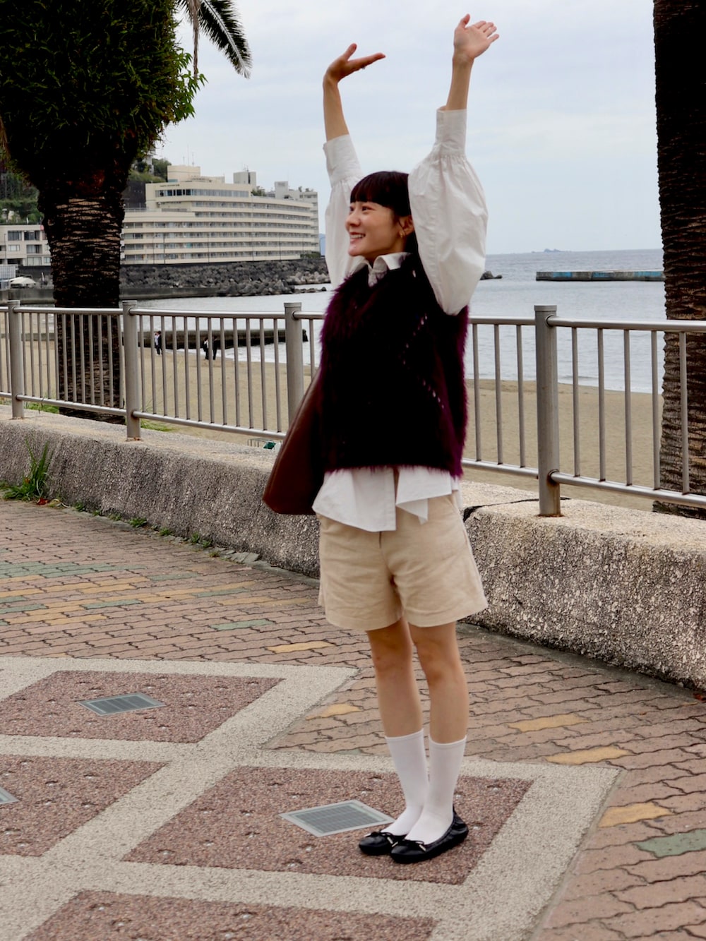 ブラウン系のトートバッグ、ホワイト系のシャツ/ブラウス、レッド系のニット/セーターを着用したレディースの秋コーディネートの2枚目の写真