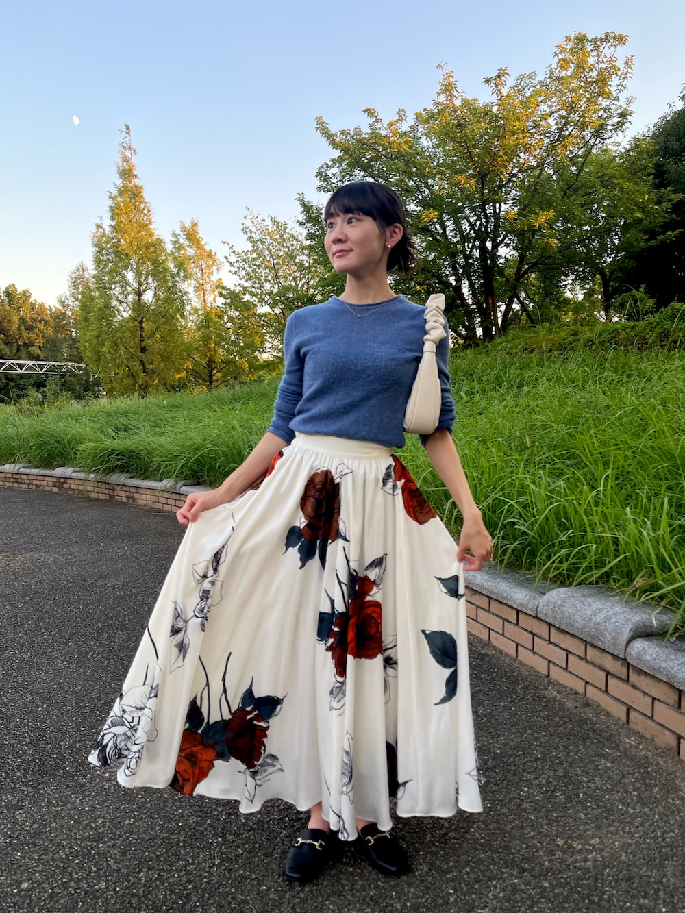 ブルー系のニット/セーター、ホワイト系のスカート、ホワイト系のショルダーバッグを着用したレディースの秋コーディネートの3枚目の写真