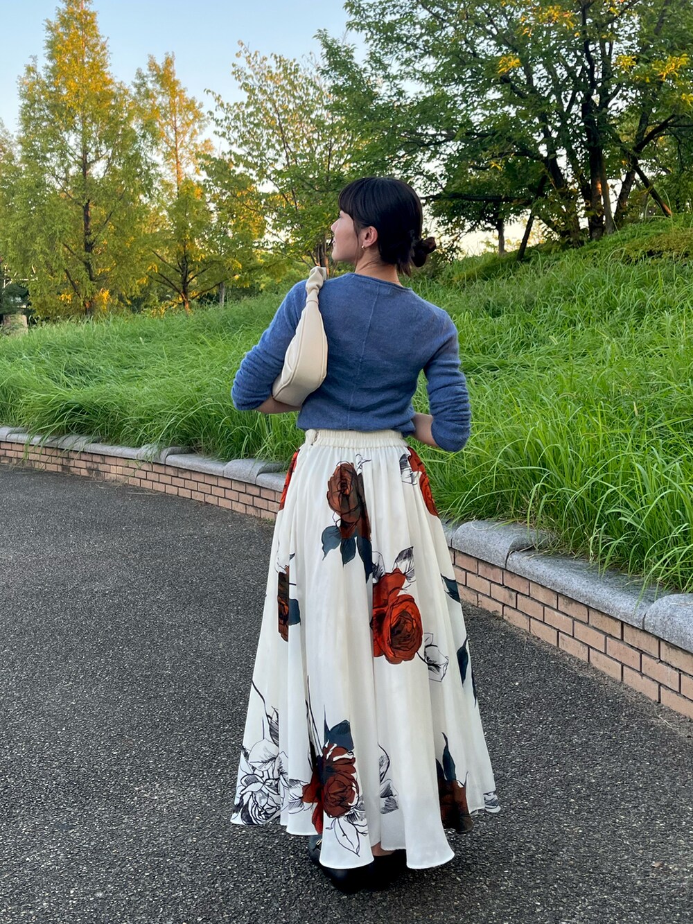 ブルー系のニット/セーター、ホワイト系のスカート、ホワイト系のショルダーバッグを着用したレディースの秋コーディネートの2枚目の写真