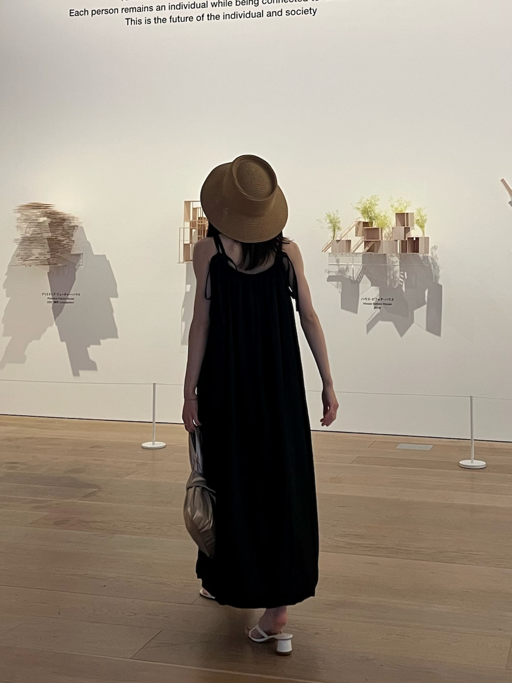 ゴールド系のハンドバッグ、ブラック系のワンピース、ホワイト系のサンダルを着用したレディースの夏コーディネートの2枚目の写真