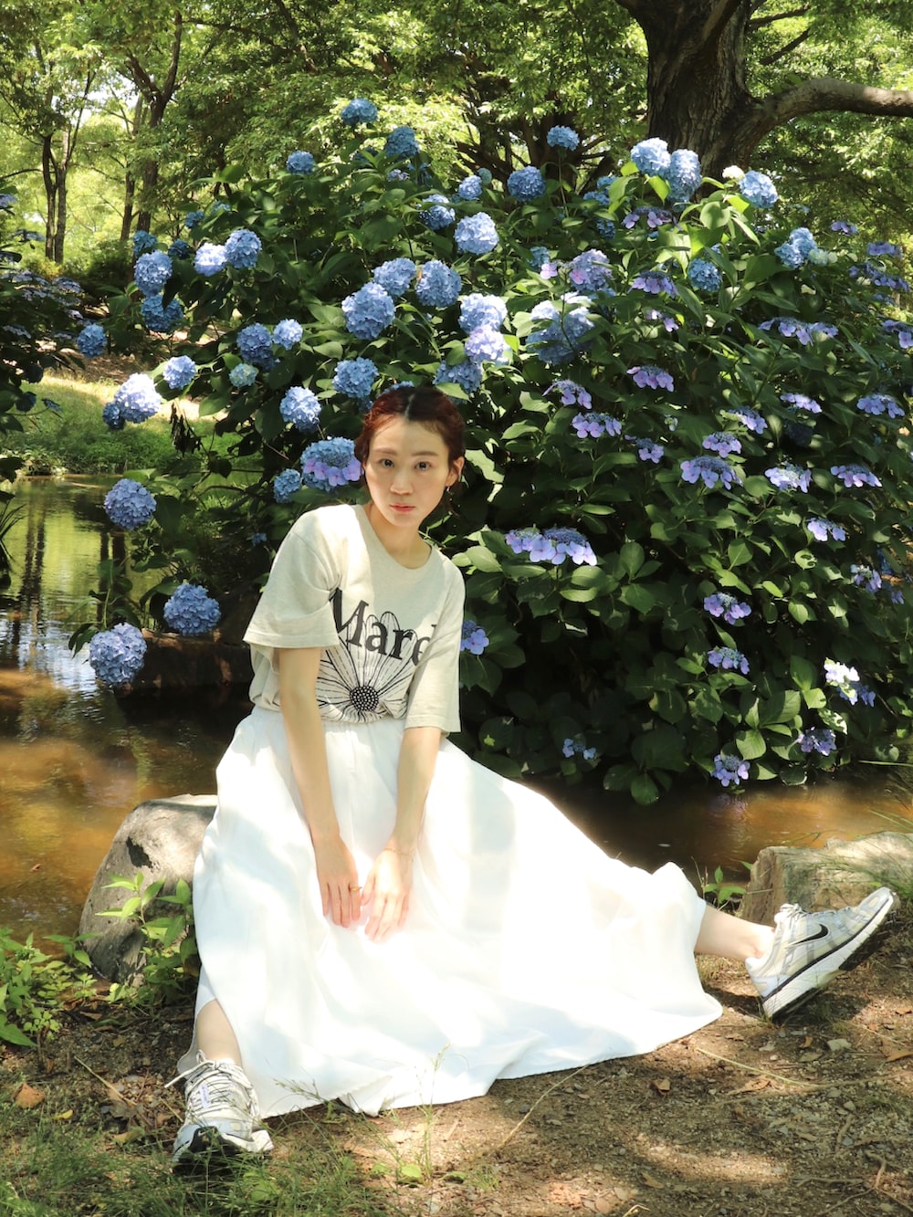 シルバー系のスニーカー、ホワイト系のスカート、ベージュ系のTシャツ/カットソーを着用したレディースの夏コーディネートの2枚目の写真