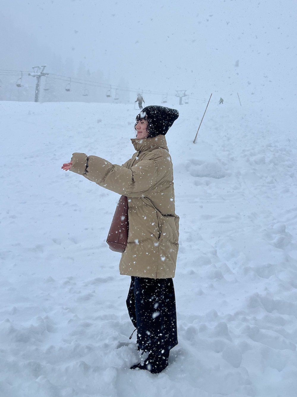 ブラック系のその他パンツ、ベージュ系のダウンジャケット/コート、ブラウン系のショルダーバッグを着用したレディースの冬コーディネートの2枚目の写真