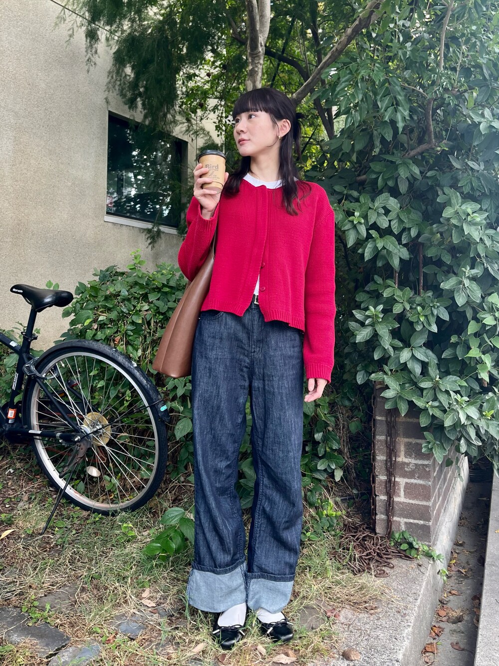 ブラウン系のバッグ、レッド系のカーディガン/ボレロ、ブルー系のデニムパンツを着用したレディースの秋コーディネートの2枚目の写真