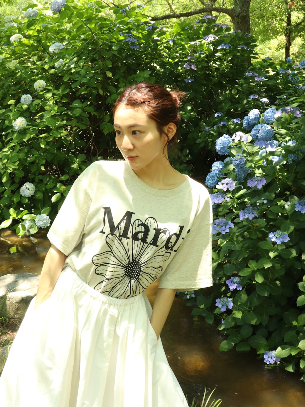 シルバー系のスニーカー、ホワイト系のスカート、ベージュ系のTシャツ/カットソーを着用したレディースの夏コーディネートの3枚目の写真