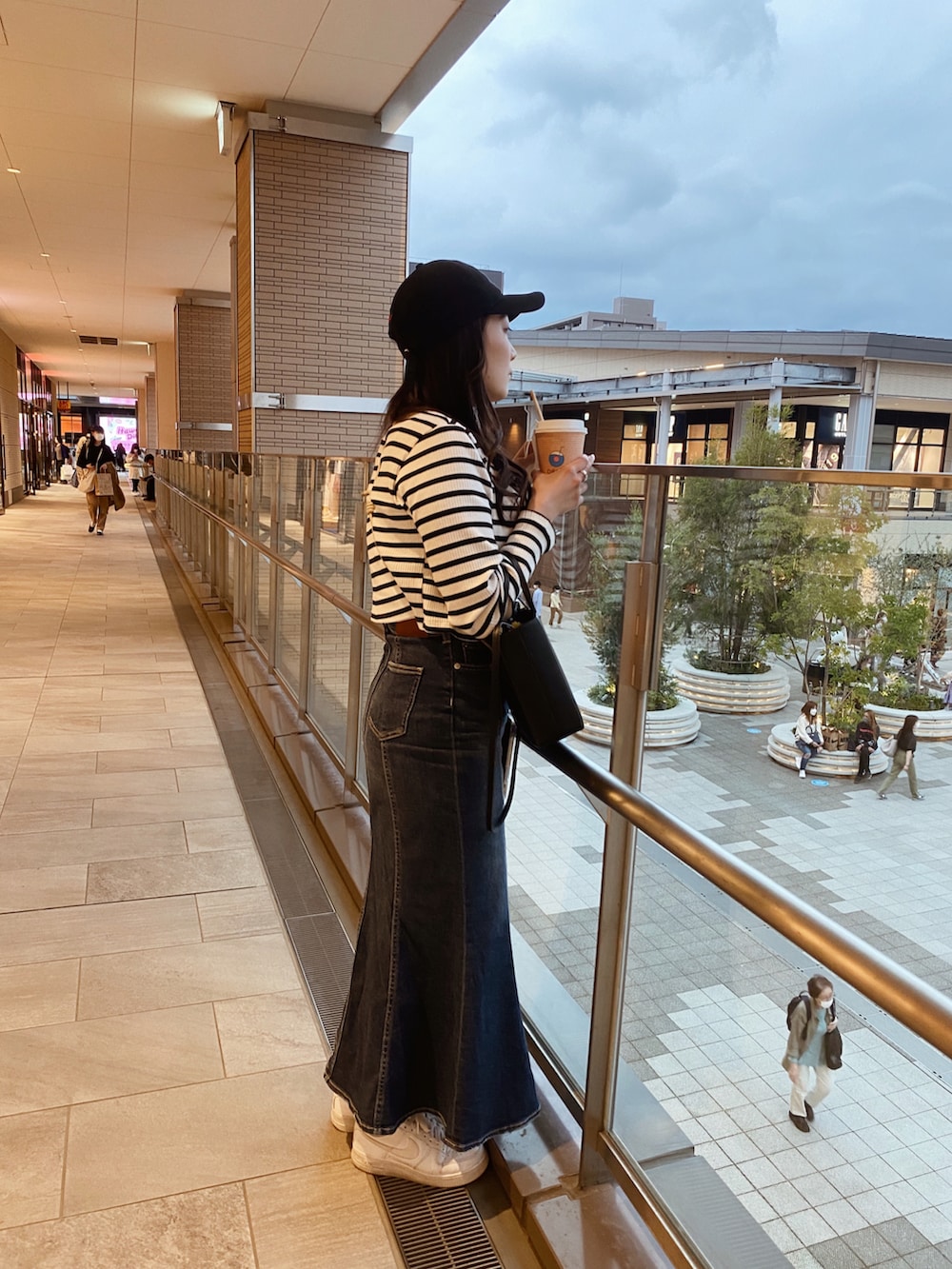 ホワイト系のスニーカー、ブルー系のデニムスカート、ホワイト系のアンサンブルを着用したレディースの夏コーディネートの2枚目の写真