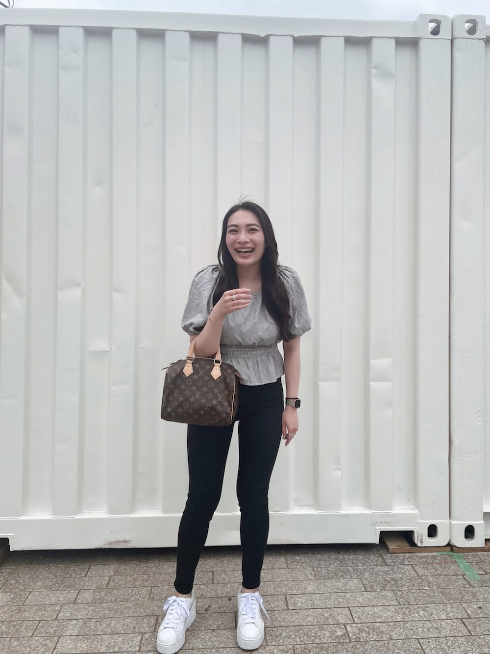 ブラック系のデニムパンツ、ホワイト系のスニーカー、グレー系のトップスを着用したレディースの夏コーディネートの2枚目の写真