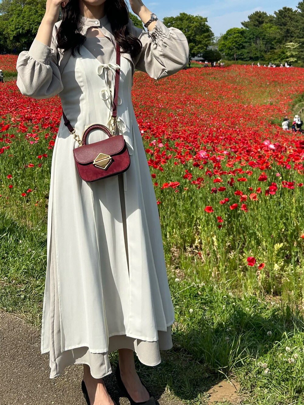 ベージュ系のワンピース、レッド系のハンドバッグ、ピンク系のパンプスを着用したレディースの春コーディネートの2枚目の写真