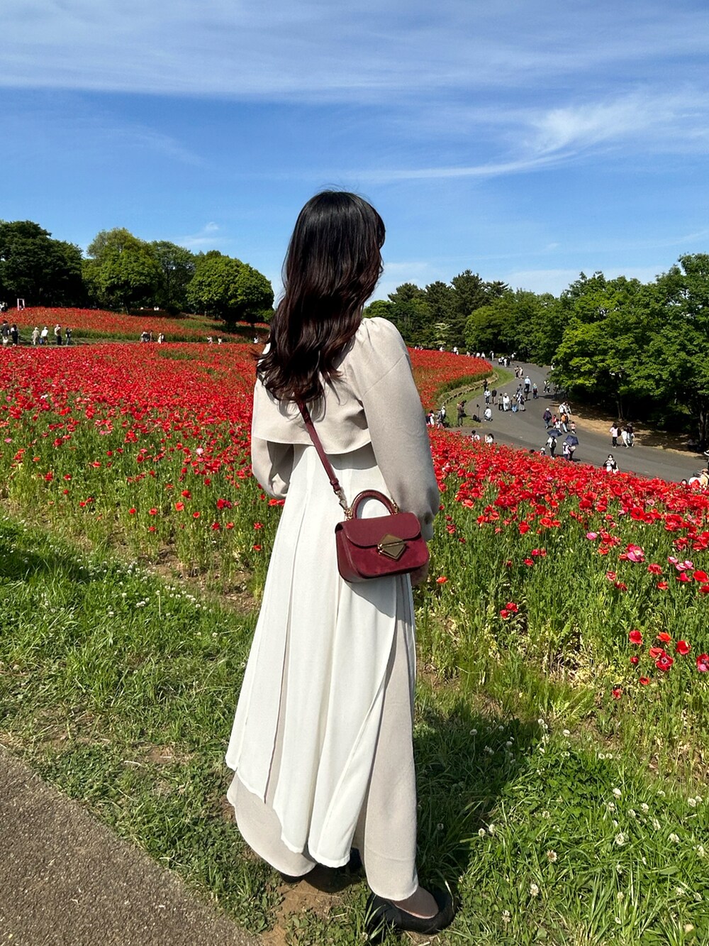 ベージュ系のワンピース、レッド系のハンドバッグ、ピンク系のパンプスを着用したレディースの春コーディネートの3枚目の写真