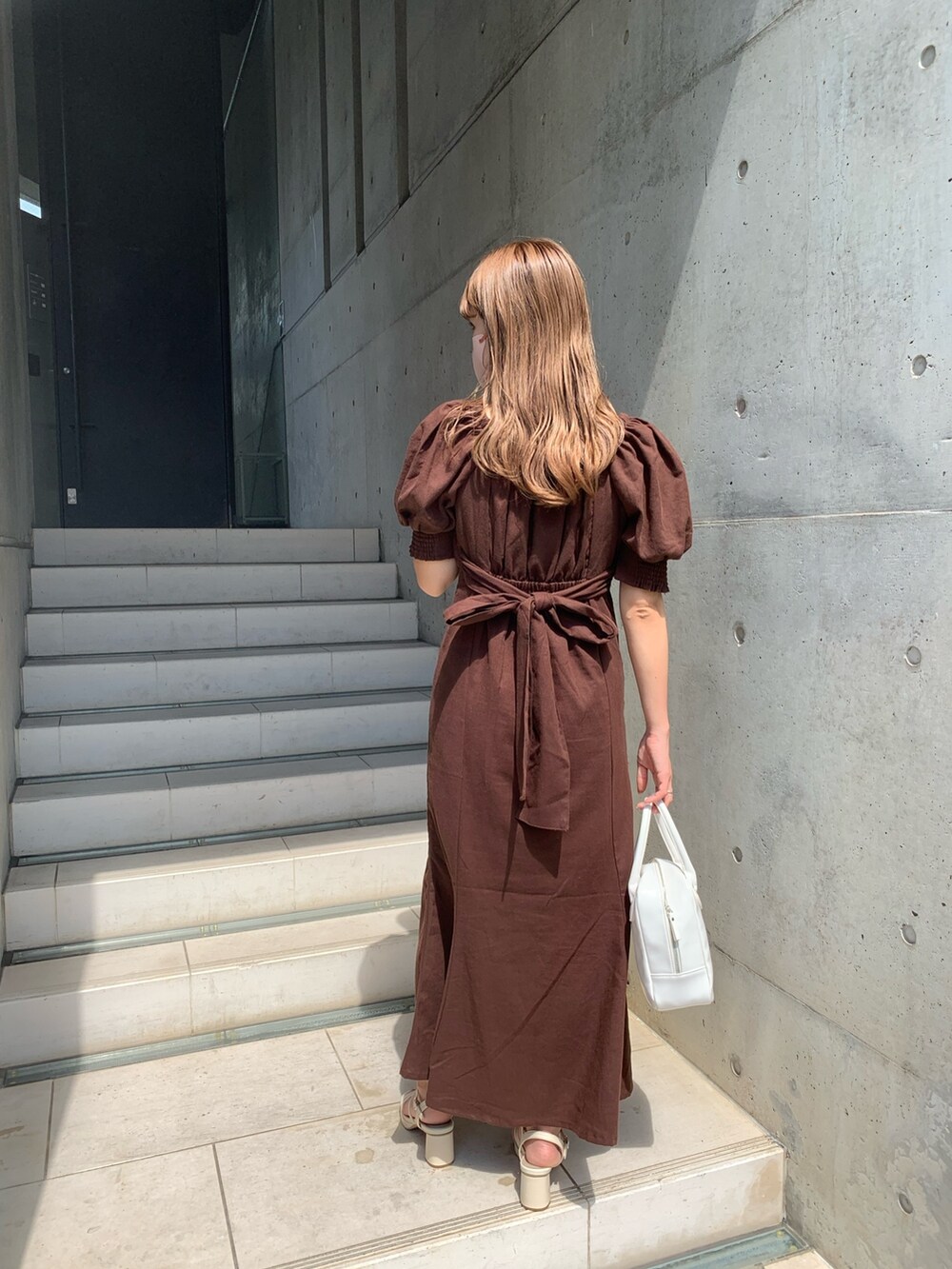 ブラウン系のワンピース、ホワイト系のショルダーバッグ、ホワイト系のサンダルを着用したレディースの夏コーディネートの2枚目の写真