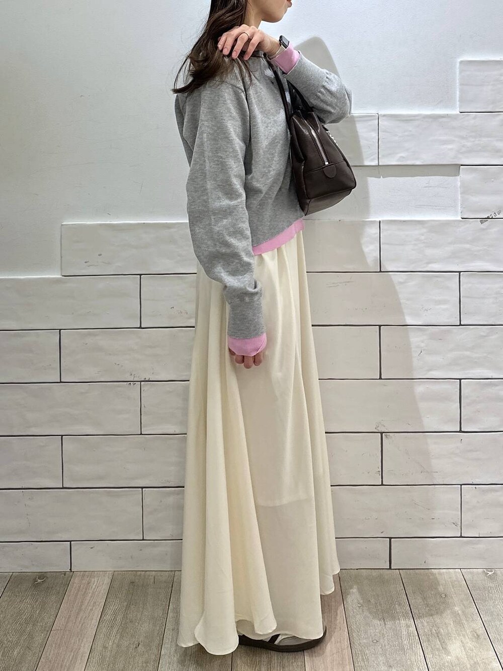 ブラウン系のボストンバッグ、ホワイト系のスカート、グレー系のカーディガン/ボレロを着用したレディースの冬コーディネートの2枚目の写真