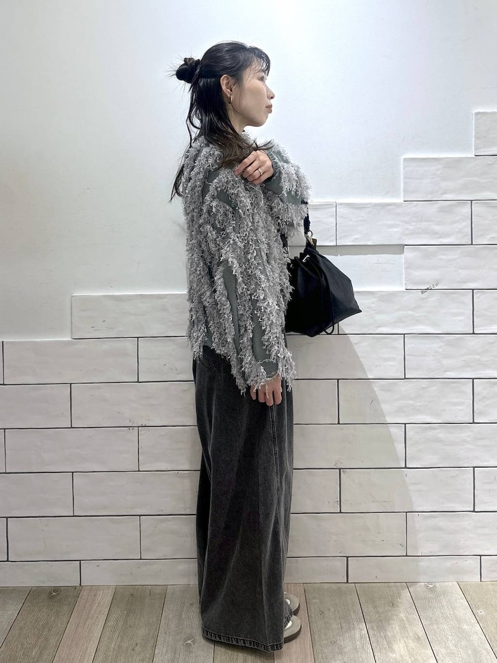 ブラック系のショルダーバッグ、グレー系のデニムパンツ、グリーン系のカーディガン/ボレロを着用したレディースの冬コーディネートの2枚目の写真