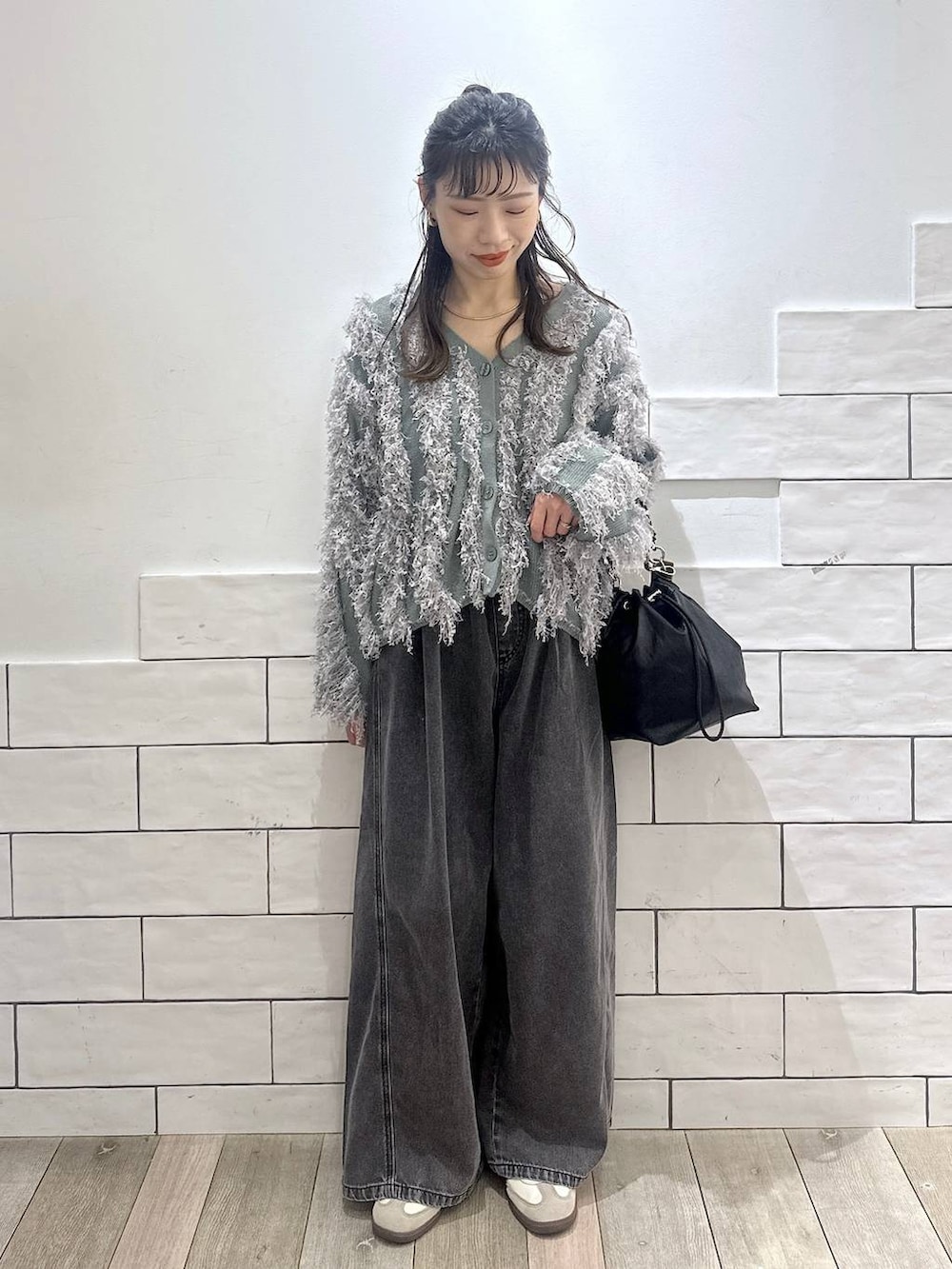 ブラック系のショルダーバッグ、グレー系のデニムパンツ、グリーン系のカーディガン/ボレロを着用したレディースの冬コーディネートの4枚目の写真