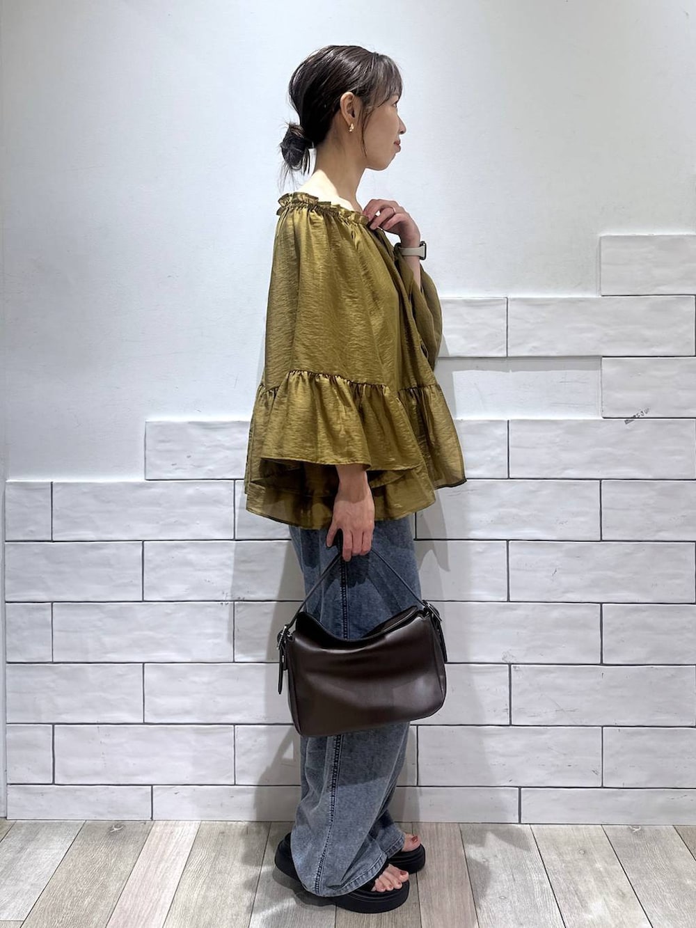 ブルー系のデニムパンツ、ブラック系のサンダル、ブラウン系のショルダーバッグを着用したレディースの夏コーディネートの3枚目の写真