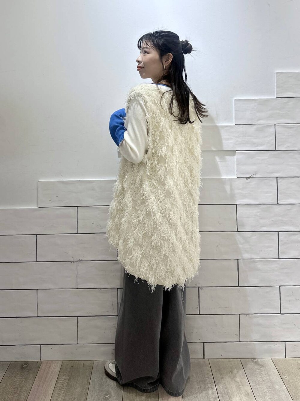 グレー系のデニムパンツ、ホワイト系のニット/セーター、ホワイト系のベストを着用したレディースの冬コーディネートの3枚目の写真