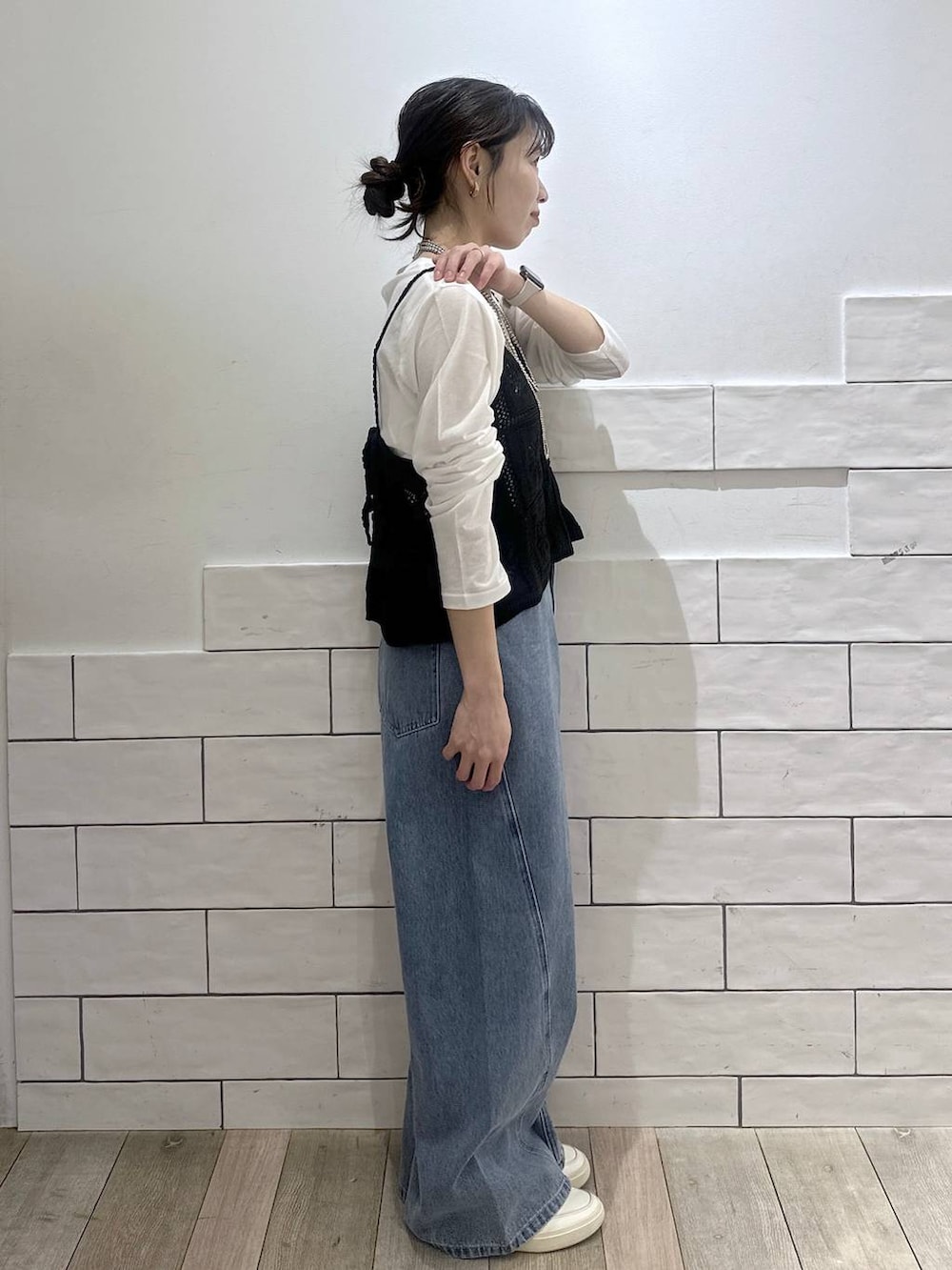 ホワイト系のTシャツ/カットソー、ブルー系のデニムパンツ、ブラック系のキャミソールを着用したレディースの冬コーディネートの3枚目の写真