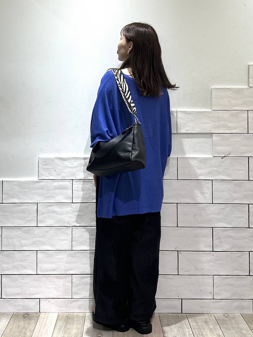 ブラック系のショルダーバッグ、ブルー系のニット/セーター、ブラック系のその他パンツを着用したレディースの春コーディネートの4枚目の写真
