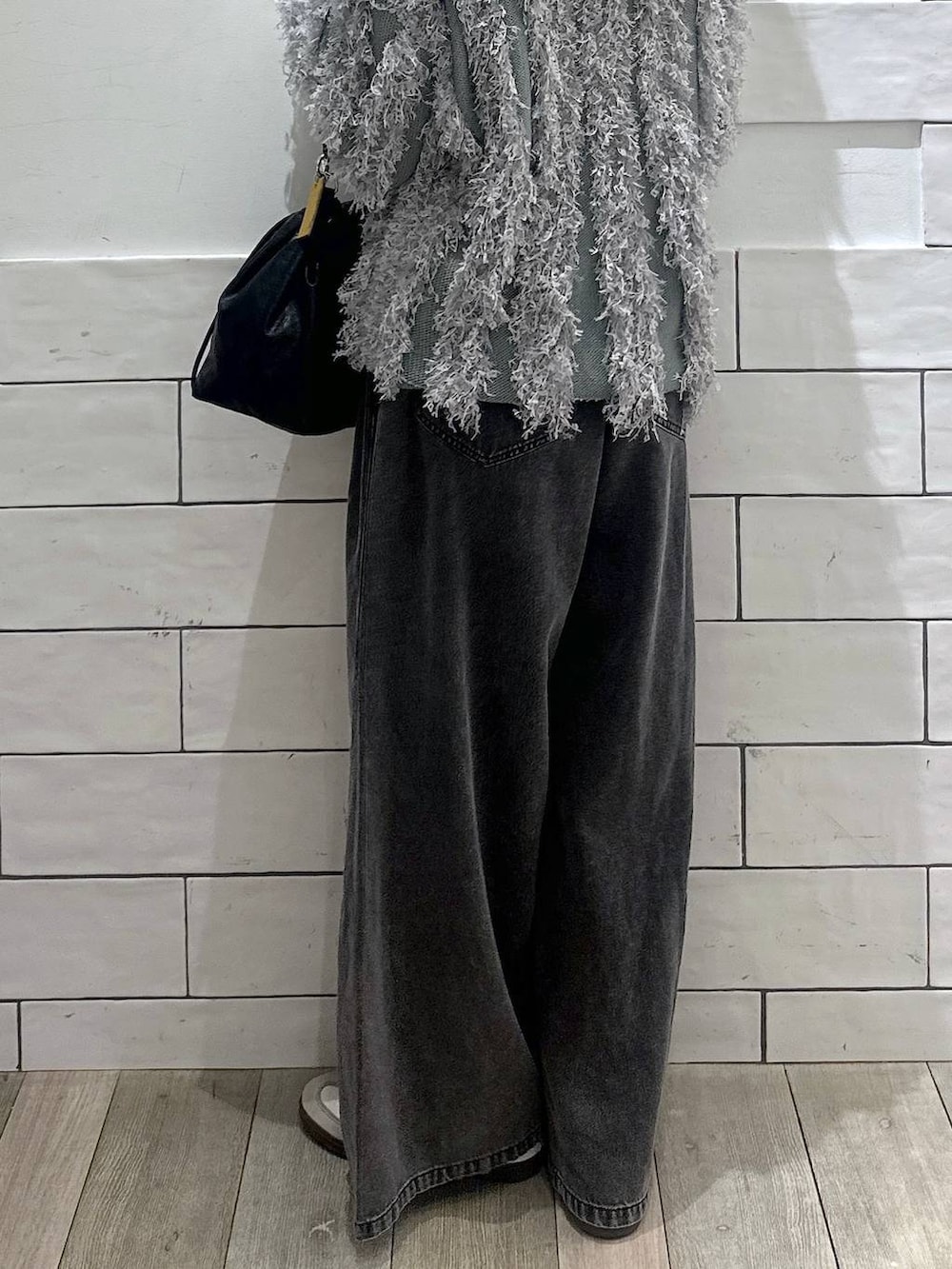 ブラック系のショルダーバッグ、グレー系のデニムパンツ、グリーン系のカーディガン/ボレロを着用したレディースの冬コーディネートの3枚目の写真