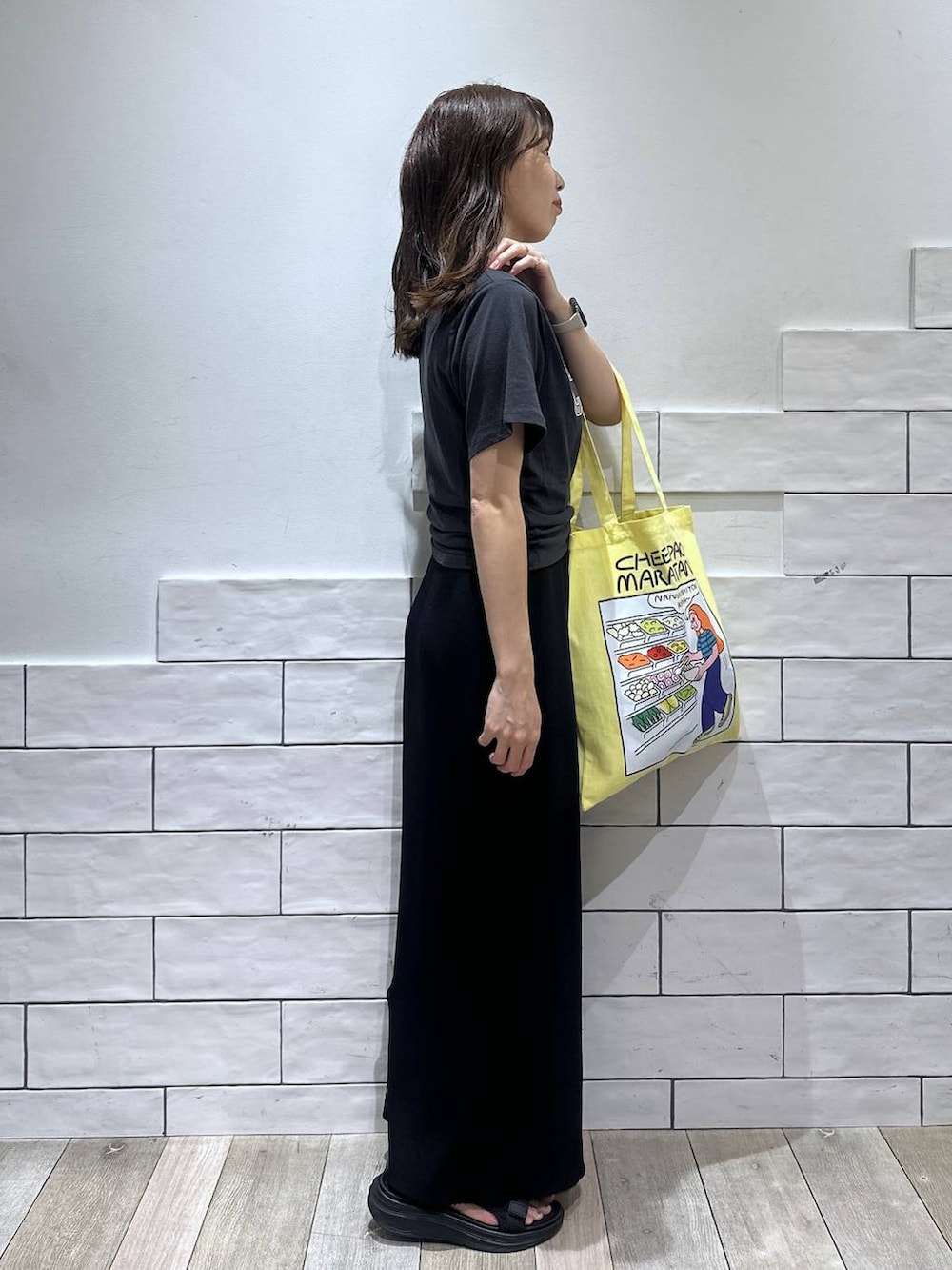 ブラック系のスカート、グレー系のTシャツ/カットソー、イエロー系のトートバッグを着用したレディースの春コーディネートの2枚目の写真