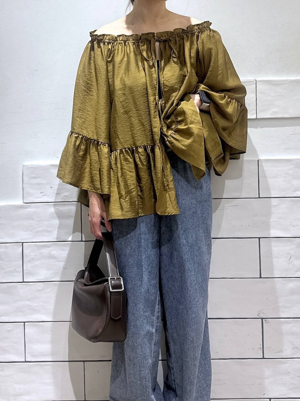 ブルー系のデニムパンツ、ブラック系のサンダル、ブラウン系のショルダーバッグを着用したレディースの夏コーディネートの2枚目の写真