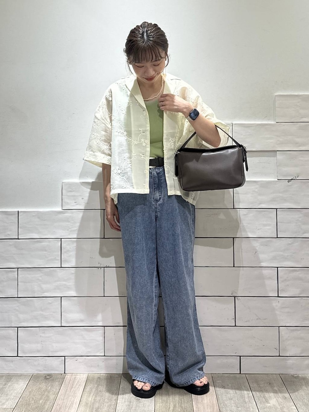 ブルー系のデニムパンツ、ブラック系のサンダル、ブラウン系のショルダーバッグを着用したレディースの夏コーディネートの4枚目の写真