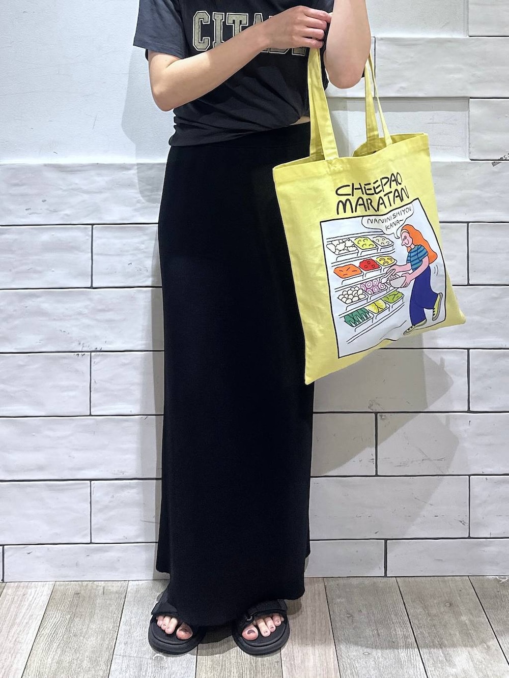 ブラック系のスカート、グレー系のTシャツ/カットソー、イエロー系のトートバッグを着用したレディースの春コーディネートの4枚目の写真