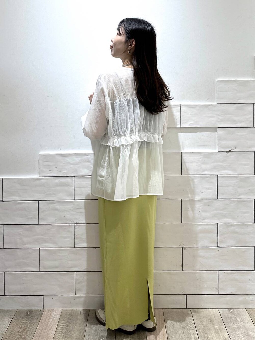 グリーン系のスカート、シルバー系のネックレスを着用したレディースの春コーディネートの2枚目の写真