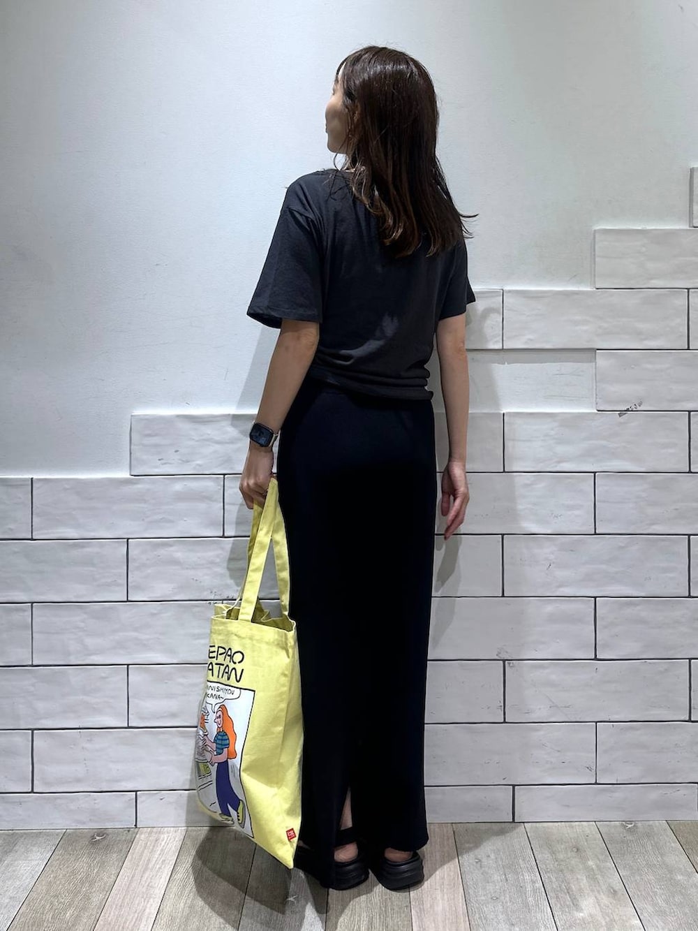 ブラック系のスカート、グレー系のTシャツ/カットソー、イエロー系のトートバッグを着用したレディースの春コーディネートの3枚目の写真