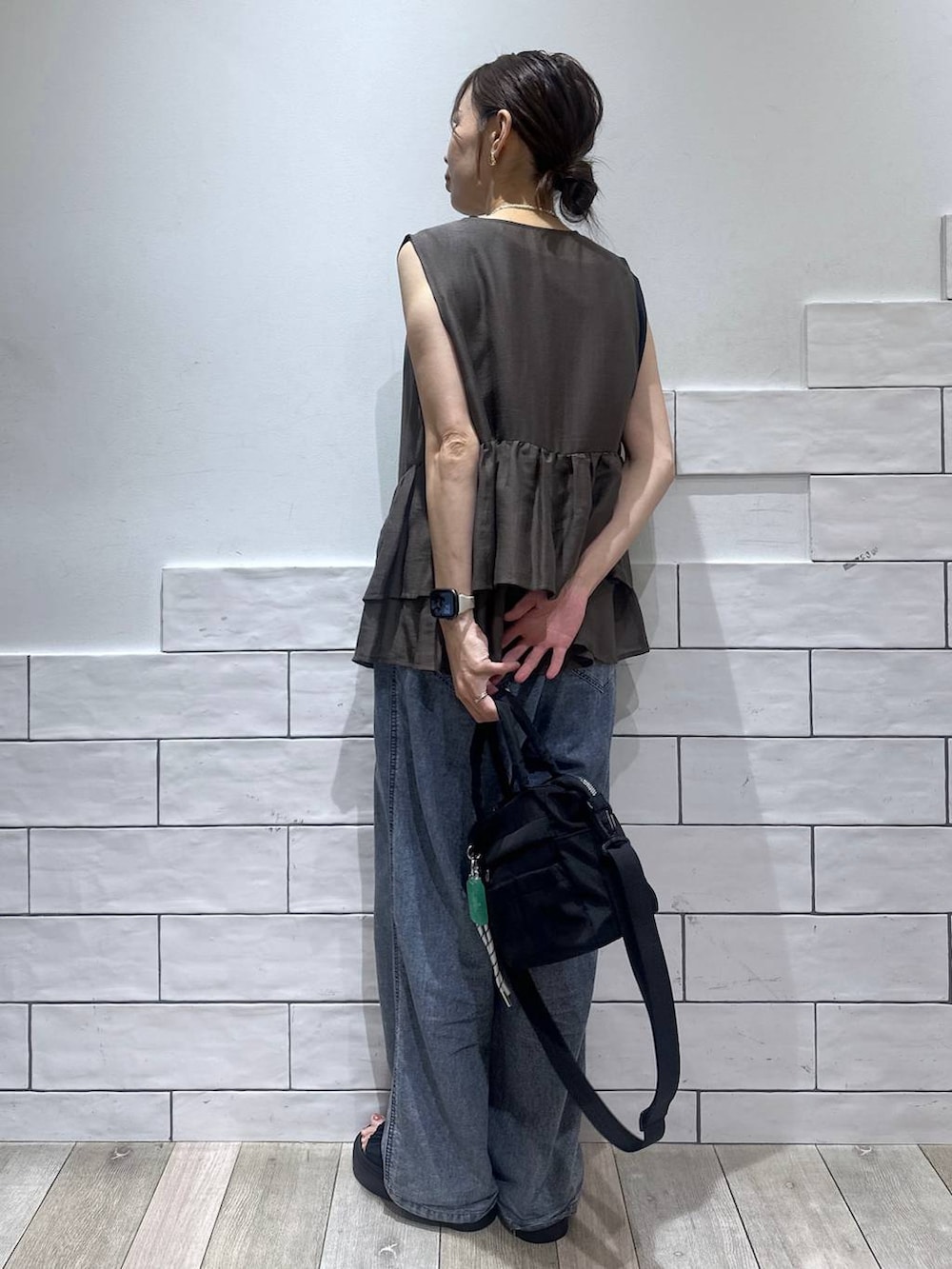 ブラック系のトートバッグ、ブルー系のデニムパンツ、ブラック系のサンダルを着用したレディースの夏コーディネートの3枚目の写真