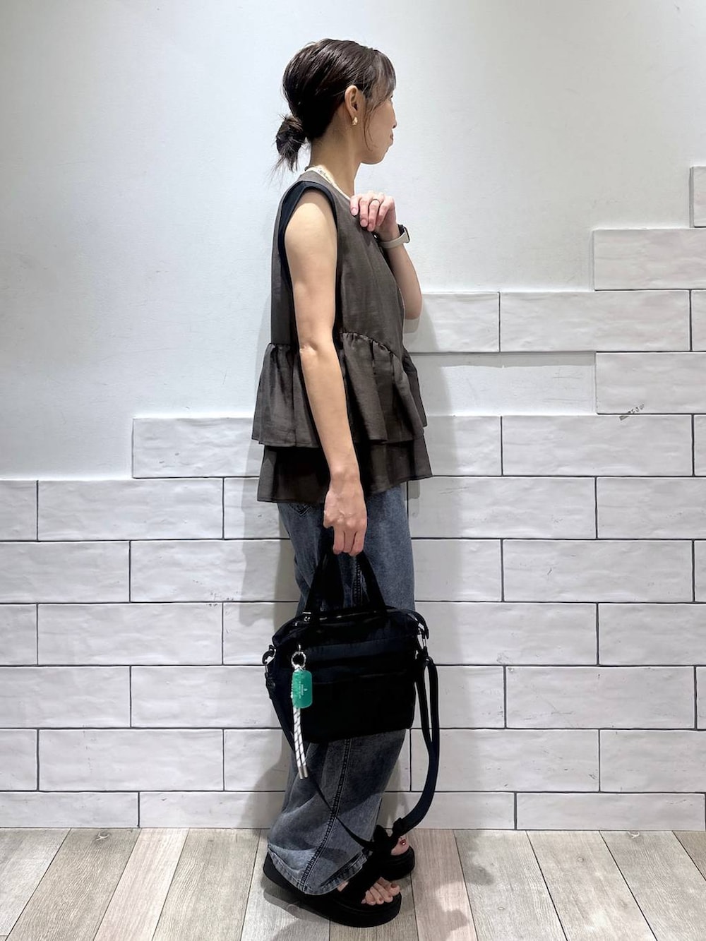 ブラック系のトートバッグ、ブルー系のデニムパンツ、ブラック系のサンダルを着用したレディースの夏コーディネートの2枚目の写真