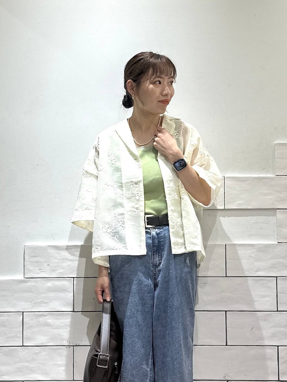ブルー系のデニムパンツ、ブラック系のサンダル、ブラウン系のショルダーバッグを着用したレディースの夏コーディネートの2枚目の写真
