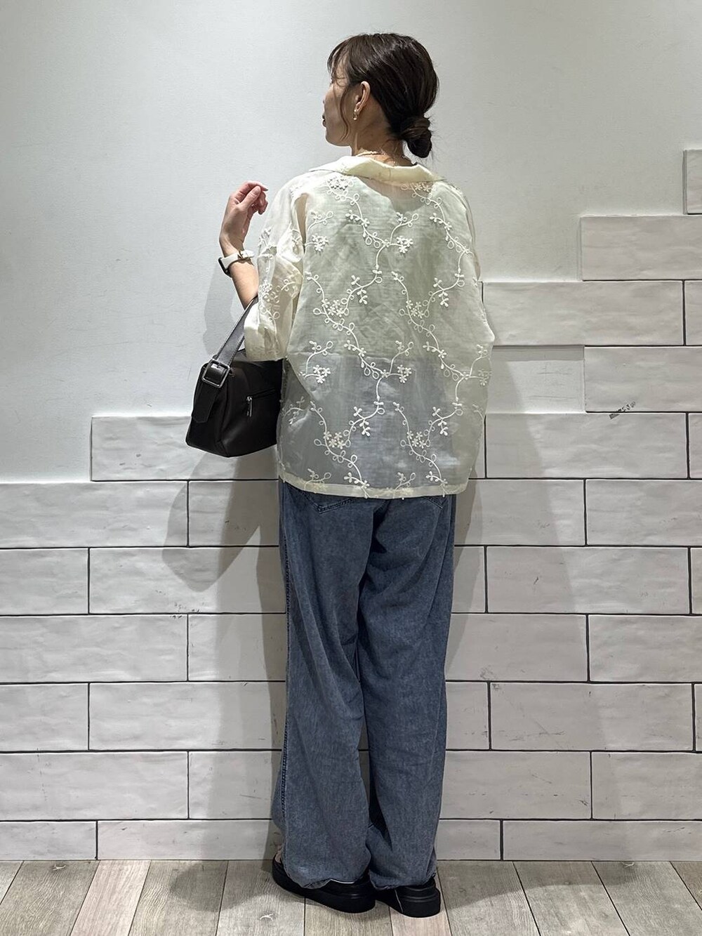 ブルー系のデニムパンツ、ブラック系のサンダル、ブラウン系のショルダーバッグを着用したレディースの夏コーディネートの5枚目の写真