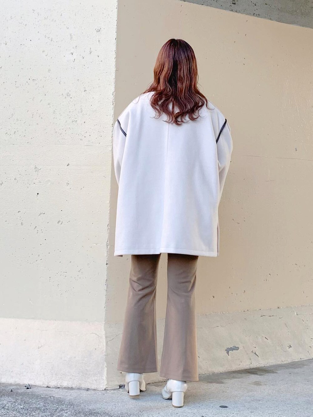 ベージュ系のノーカラーコート、ホワイト系のその他アウター、ベージュ系のその他パンツを着用したレディースの春コーディネートの3枚目の写真