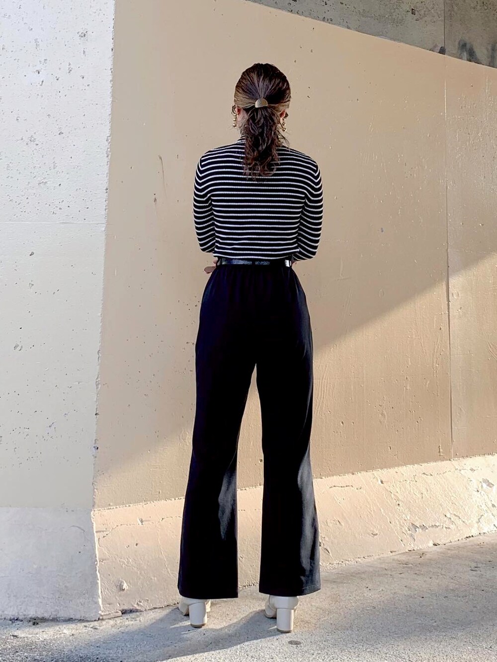 ブラック系のTシャツ/カットソー、ブラック系のトップス、ブラック系のスラックスを着用したレディースの秋コーディネートの5枚目の写真