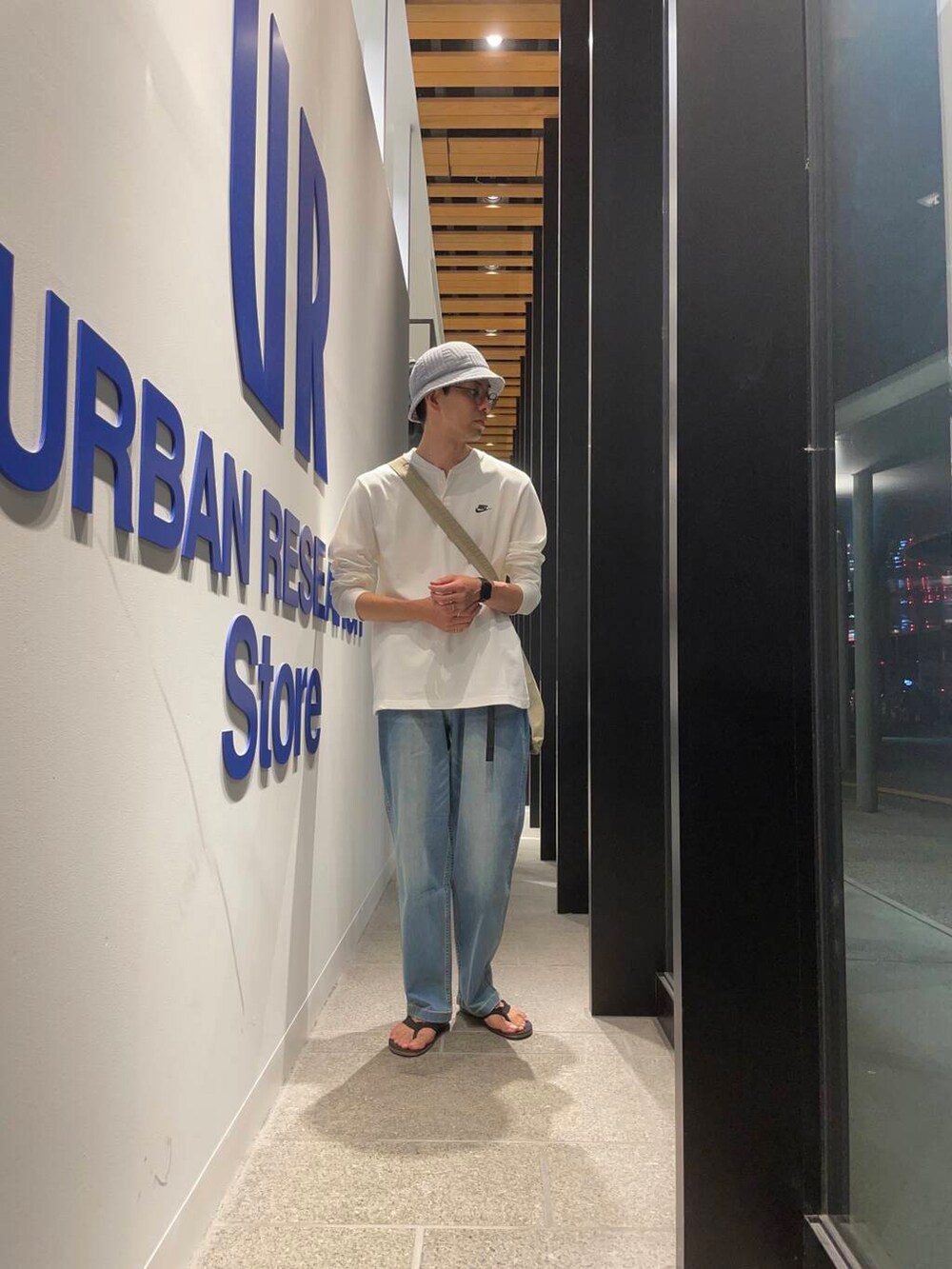 ブラック系のサンダル、グレー系のショルダーバッグ、ブルー系のデニムパンツを着用したメンズの夏コーディネートの4枚目の写真