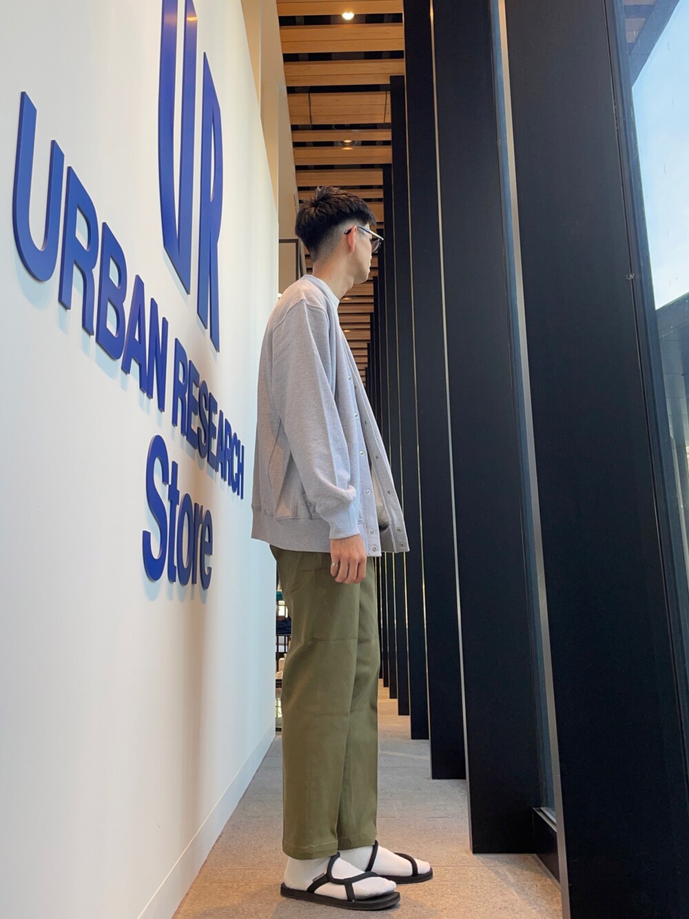 グレー系のカーディガン/ボレロ、ベージュ系のTシャツ/カットソー、グリーン系のチノパンツを着用したメンズの秋コーディネートの2枚目の写真