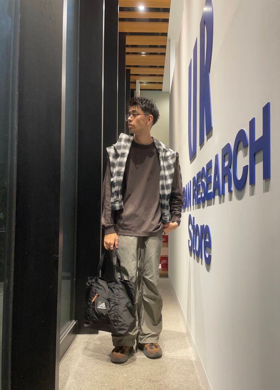 ブラック系のトートバッグ、ブラック系のシャツ/ブラウス、ブラウン系のTシャツ/カットソーを着用したメンズの秋コーディネートの2枚目の写真