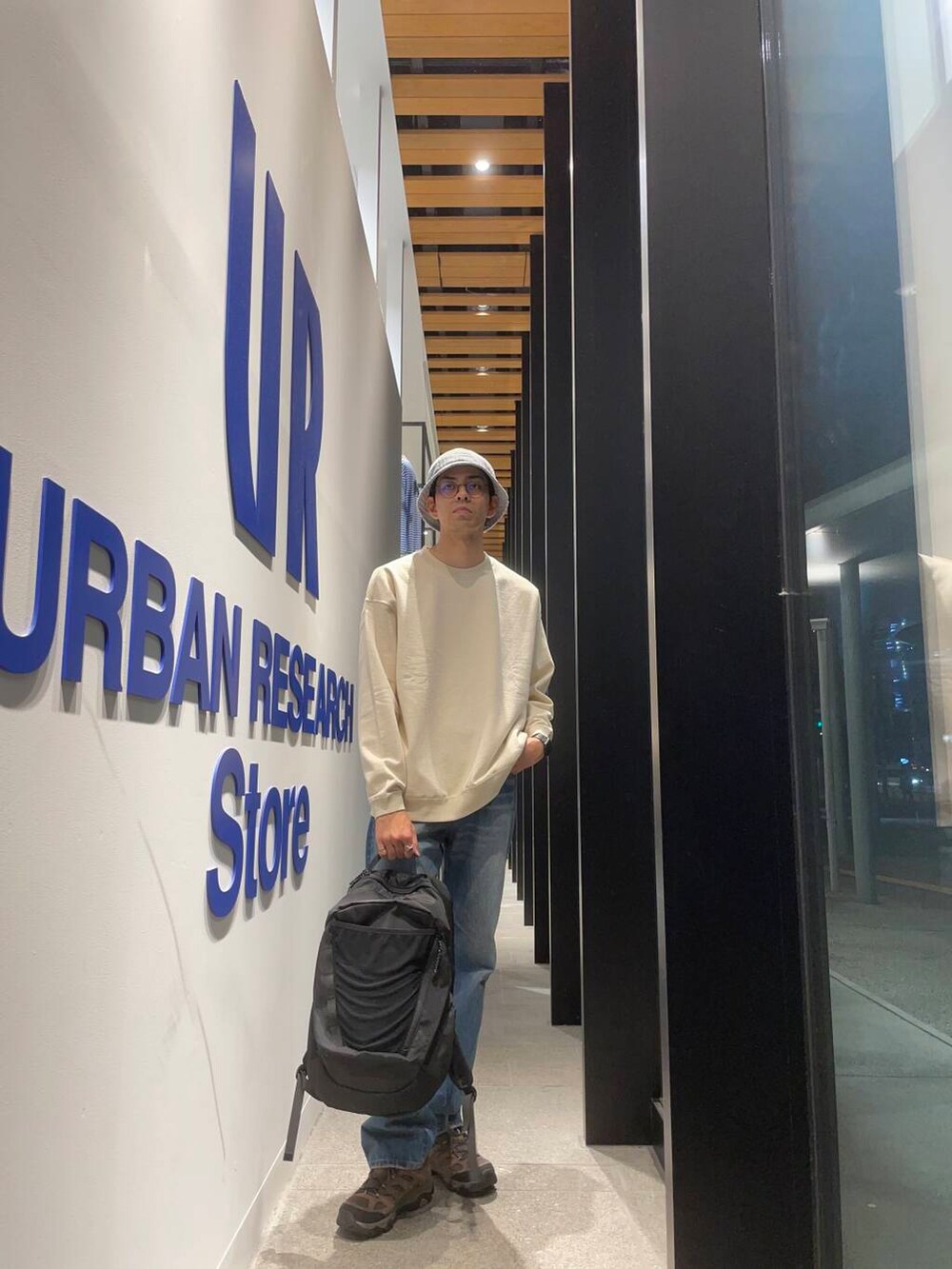 ブラック系のバックパック/リュック、ブルー系のデニムパンツ、ブラウン系のスニーカーを着用したメンズの秋コーディネートの2枚目の写真