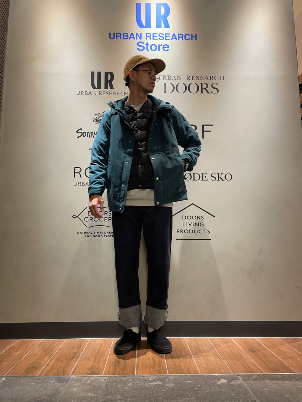 グリーン系のマウンテンパーカー、ベージュ系のスウェット、ブルー系のデニムパンツを着用したメンズの秋コーディネートの2枚目の写真