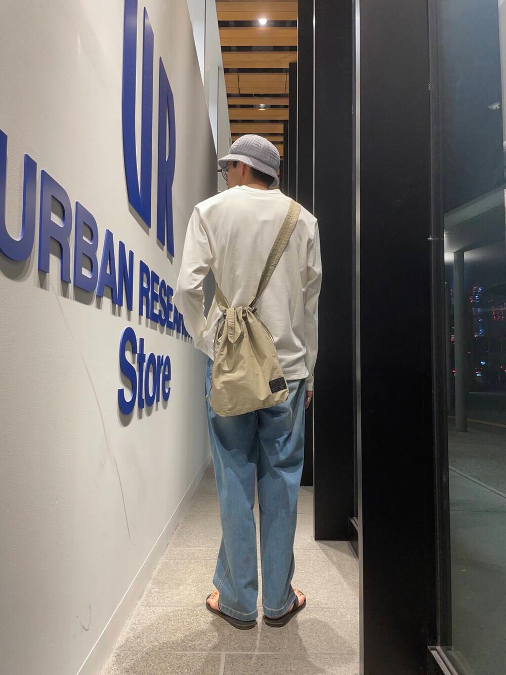 ブラック系のサンダル、グレー系のショルダーバッグ、ブルー系のデニムパンツを着用したメンズの夏コーディネートの3枚目の写真