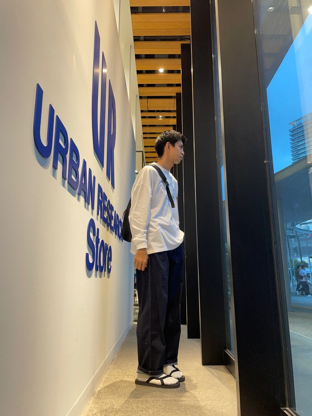 ホワイト系のTシャツ/カットソー、ブルー系のその他パンツ、ブラック系のサンダルを着用したメンズの秋コーディネートの2枚目の写真