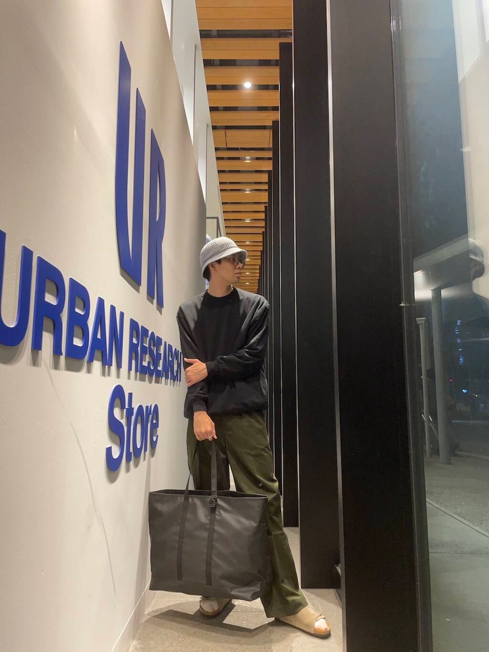 ブラック系のトートバッグ、ベージュ系のサンダル、グリーン系のその他パンツを着用したメンズの秋コーディネートの2枚目の写真