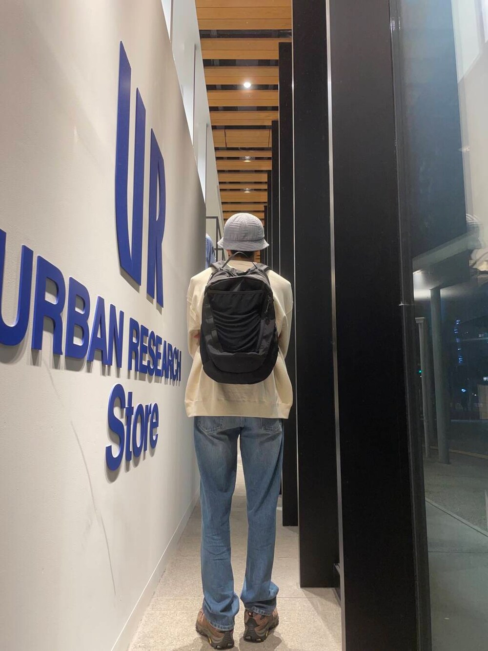 ブラック系のバックパック/リュック、ブルー系のデニムパンツ、ブラウン系のスニーカーを着用したメンズの秋コーディネートの4枚目の写真