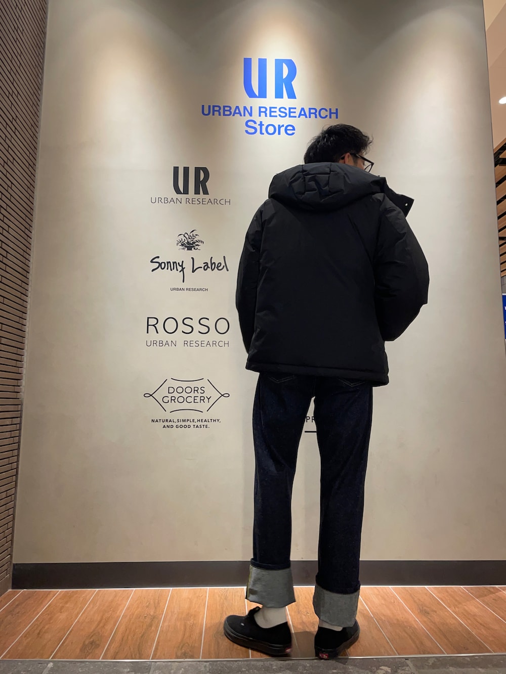 ブラック系のダウンジャケット/コート、ベージュ系のニット/セーター、ブルー系のデニムパンツを着用したメンズの冬コーディネートの2枚目の写真