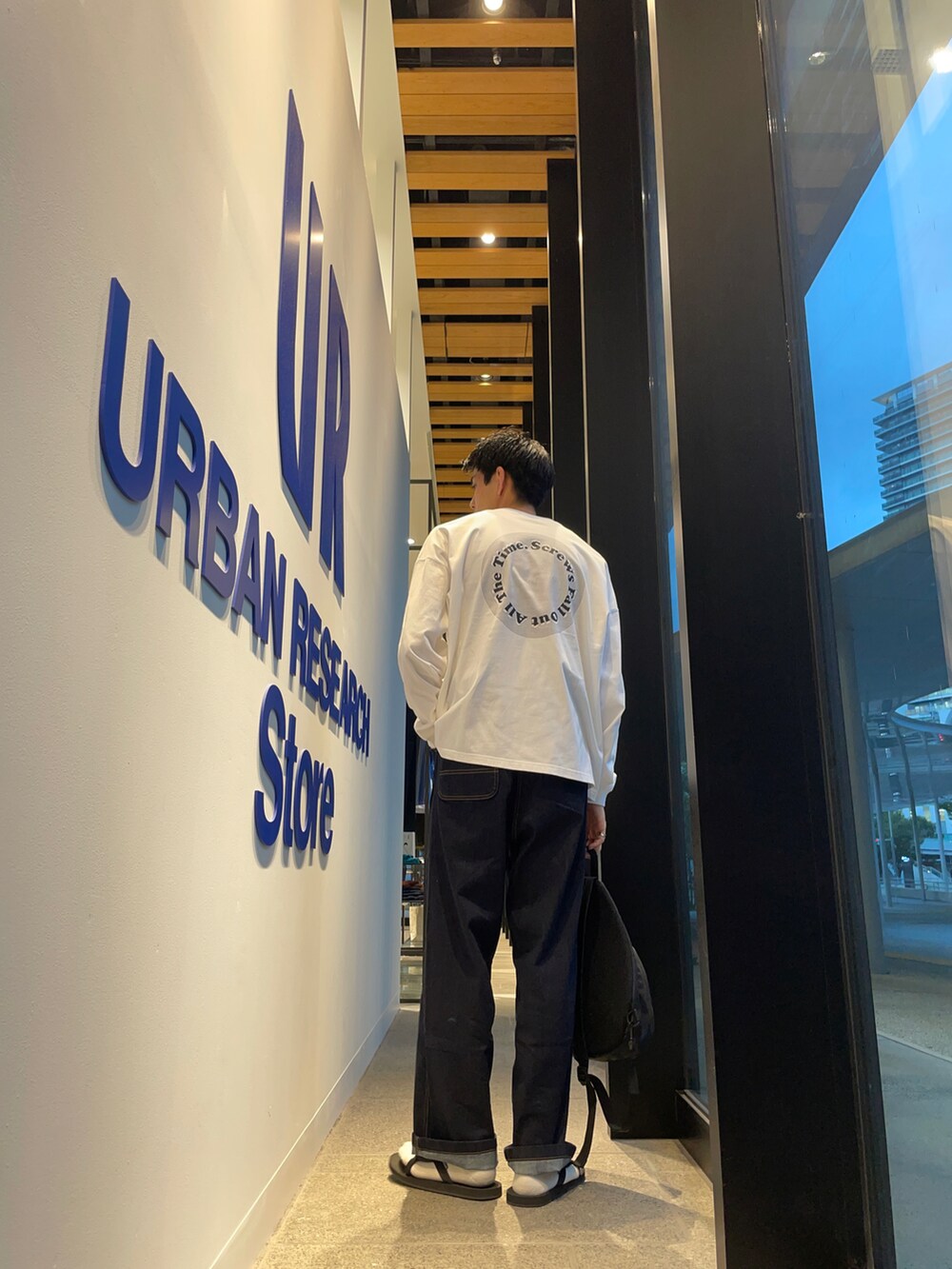 ホワイト系のTシャツ/カットソー、ブルー系のその他パンツ、ブラック系のサンダルを着用したメンズの秋コーディネートの3枚目の写真