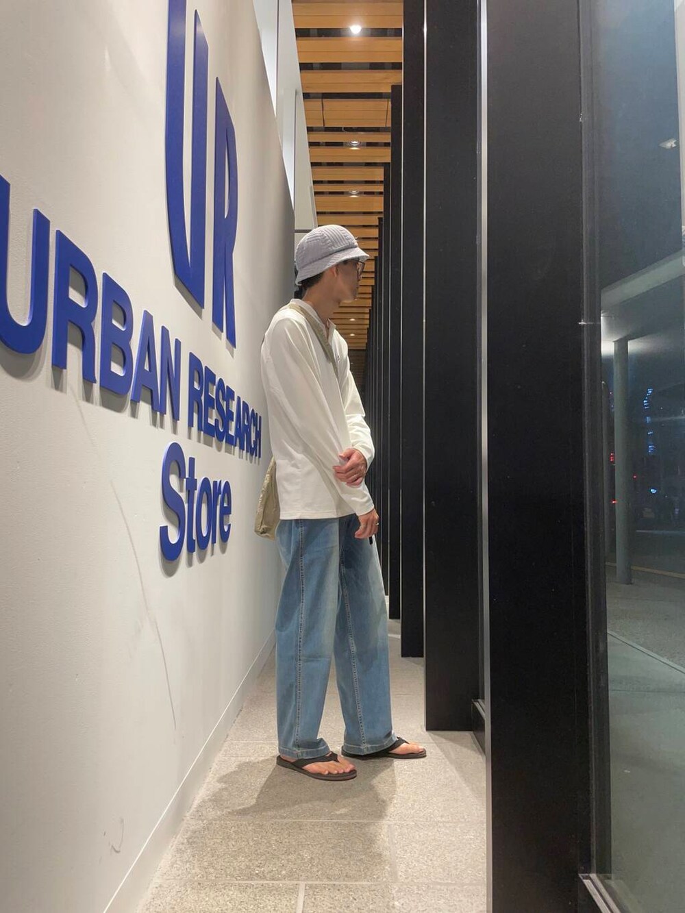 ブラック系のサンダル、グレー系のショルダーバッグ、ブルー系のデニムパンツを着用したメンズの夏コーディネートの2枚目の写真