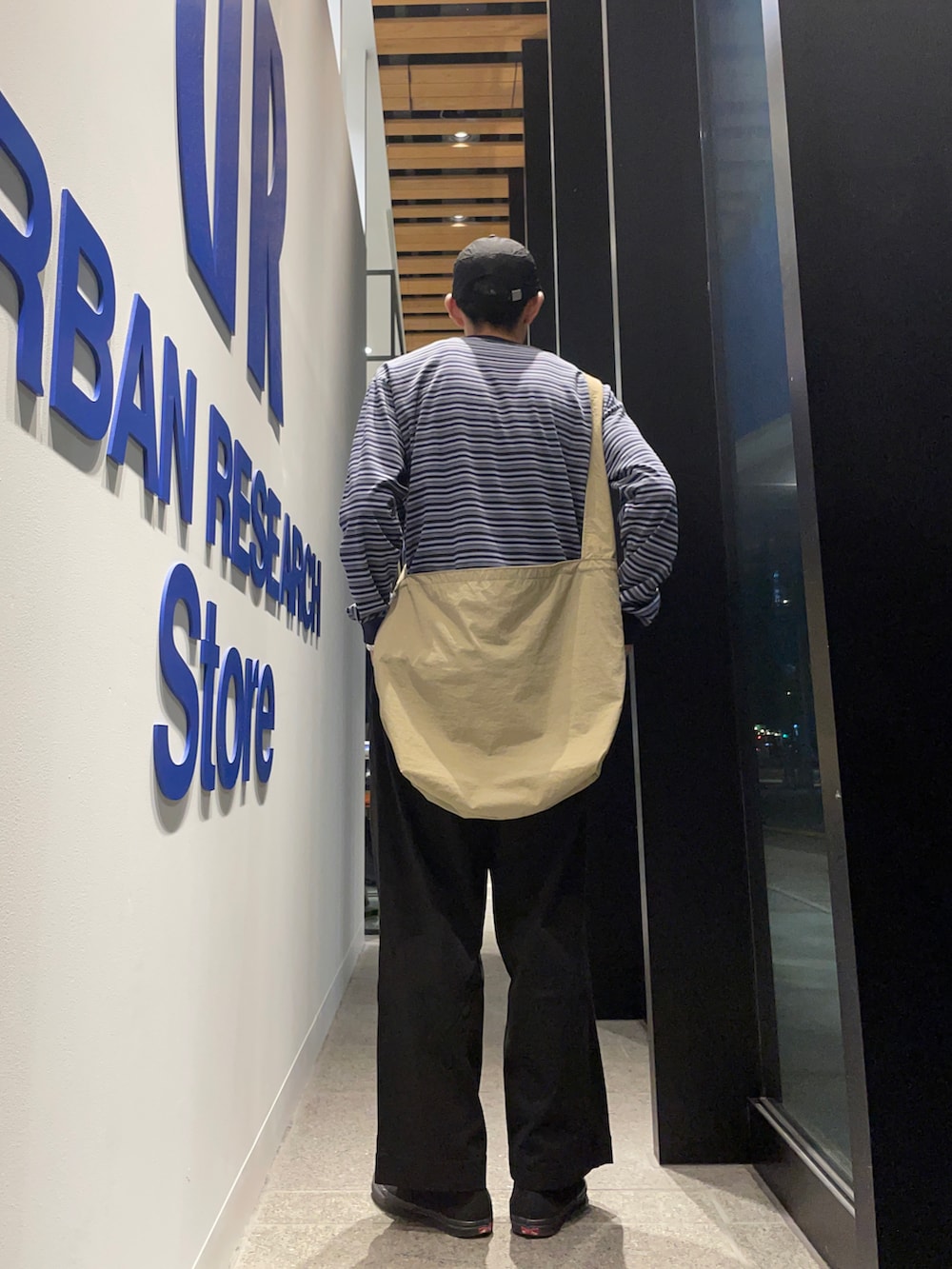 ブルー系のTシャツ/カットソー、ベージュ系のショルダーバッグ、ブラック系のチノパンツを着用したメンズの秋コーディネートの2枚目の写真