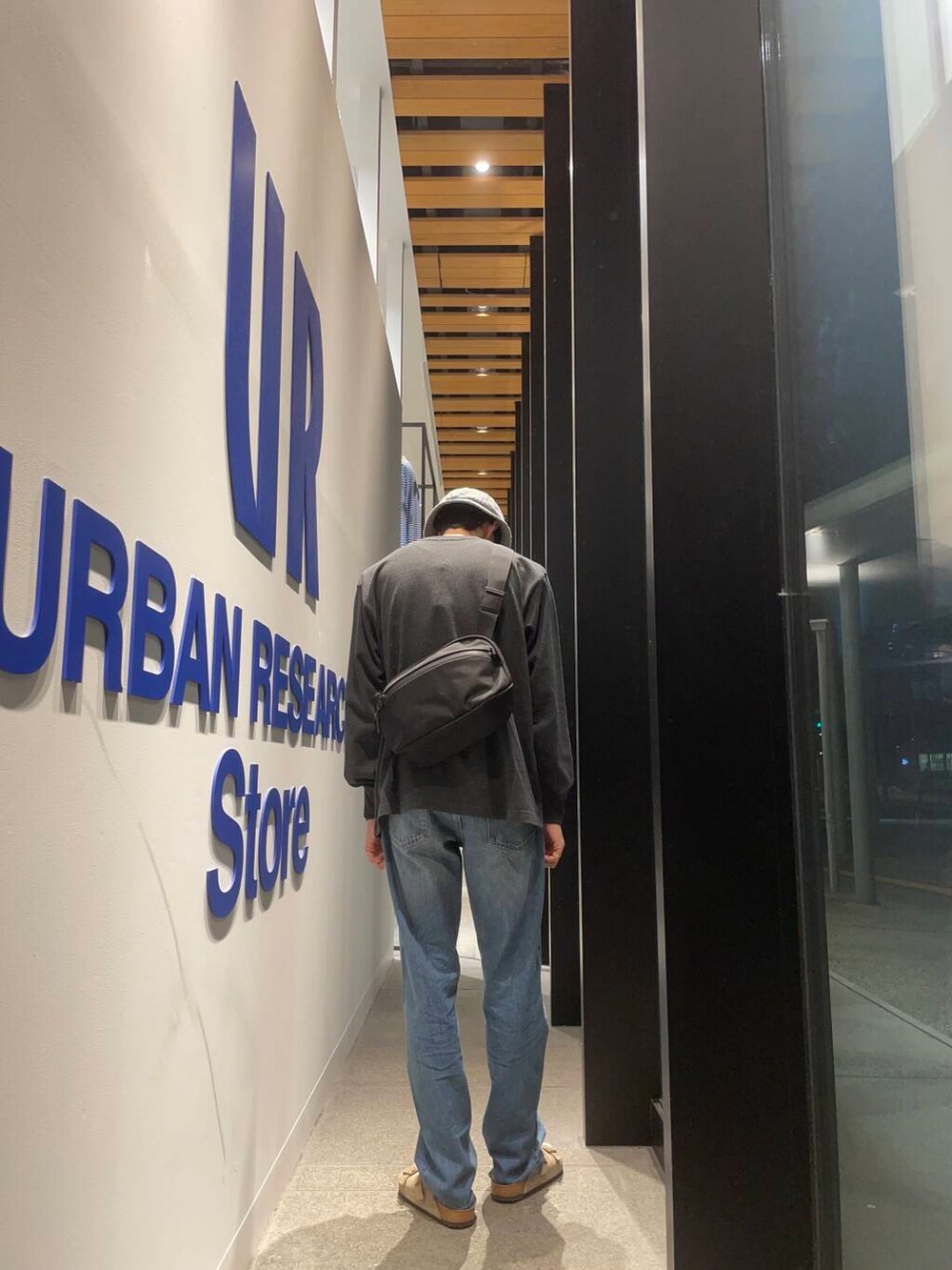 ベージュ系のサンダル、ブルー系のデニムパンツ、ブラック系のショルダーバッグを着用したメンズの秋コーディネートの4枚目の写真